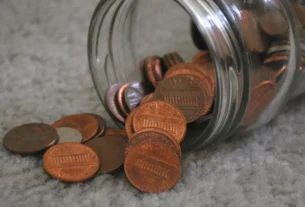 Pennies spilling out of a glass jar onto a table