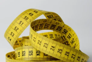 Yellow measuring tape curled on a light gray background