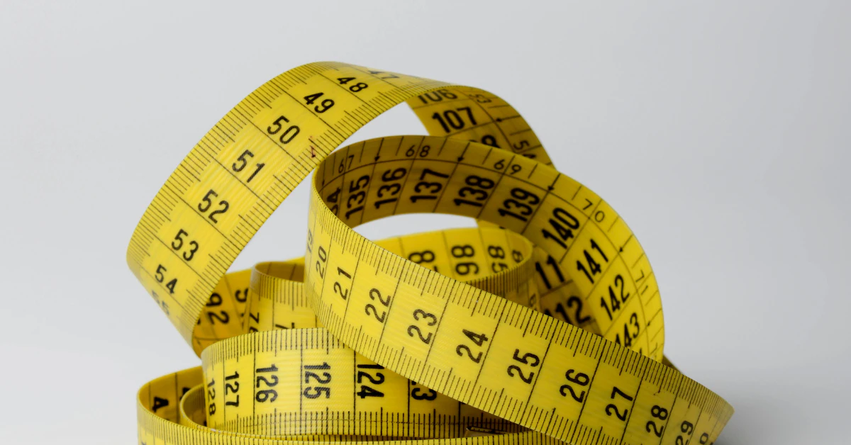 Yellow measuring tape curled on a light gray background