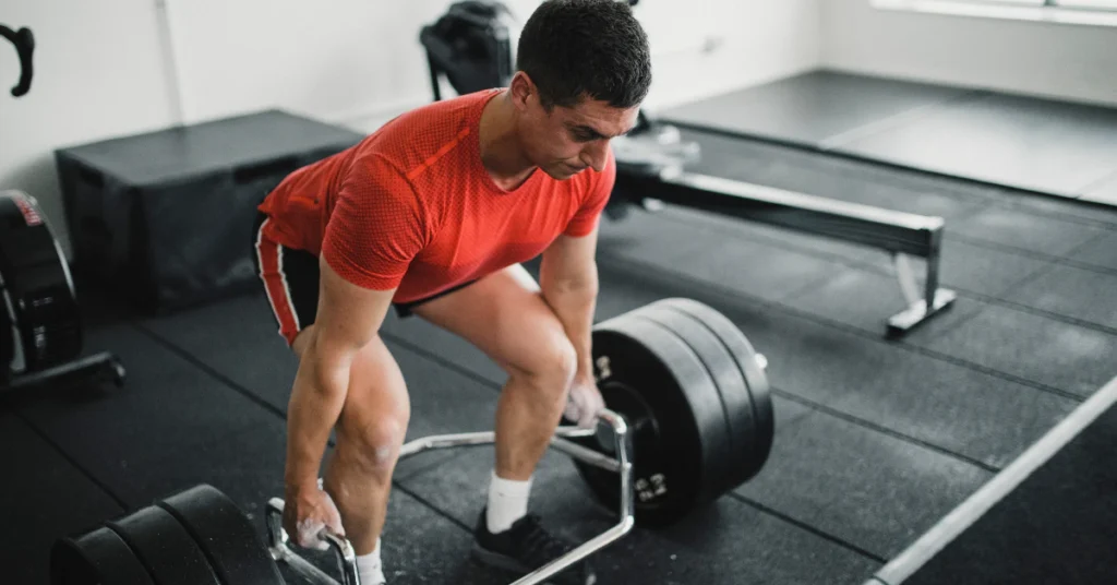 Man performing a trap bar deadlift in a gym setting