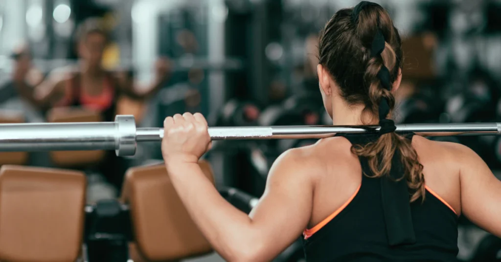 Woman gripping a barbell during a squat exercise in the gym