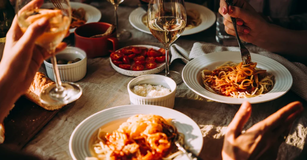 Dinner table with plates of pasta and shared dishes