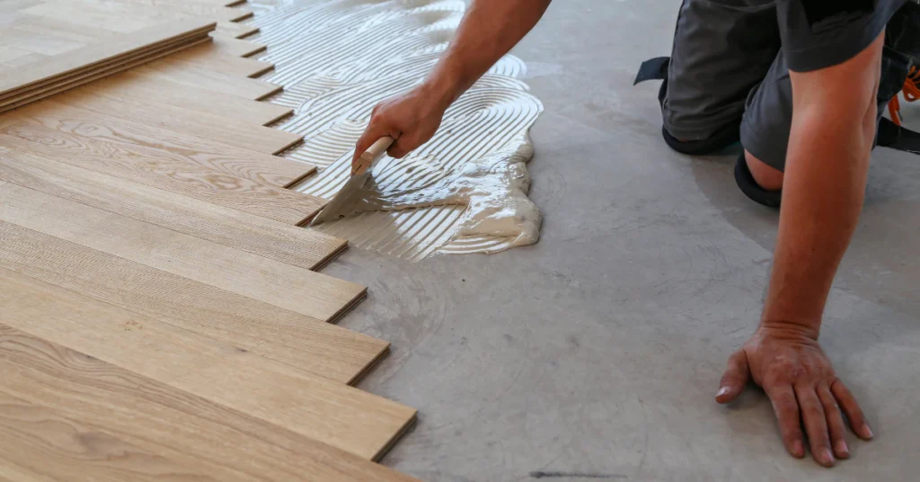 Installer laying wood flooring planks on a subfloor