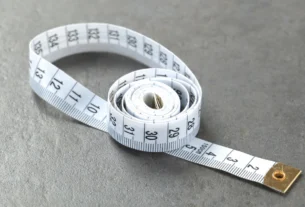 White measuring tape coiled on a gray surface