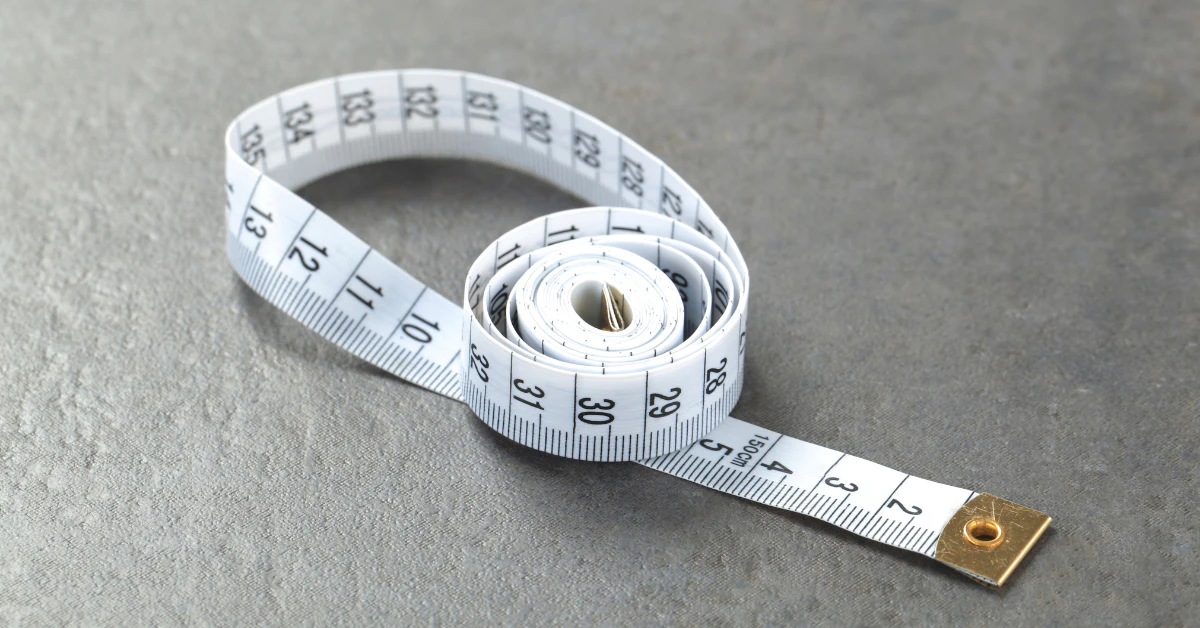 White measuring tape coiled on a gray surface