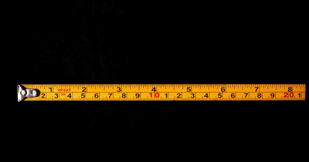 Yellow measuring tape stretched out against a black background