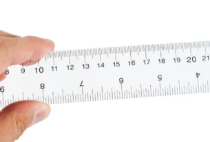 Hand holding a metal ruler to measure a centimeter