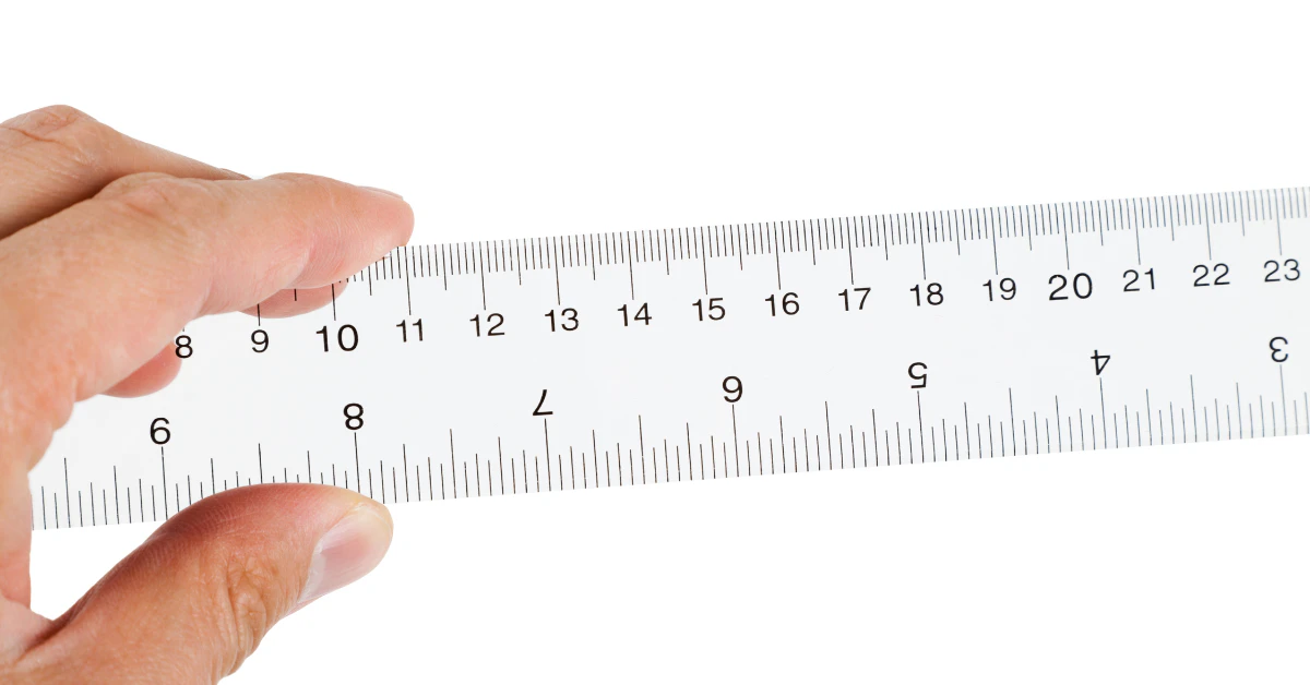 Hand holding a white ruler showing centimeter markings, used to measure 20 cm in length