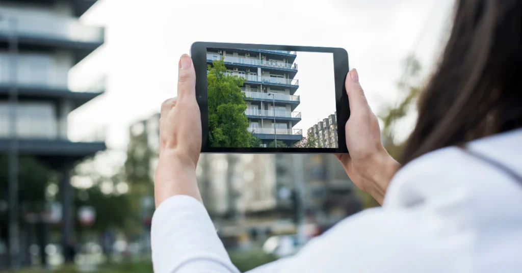 Person holding a tablet upright outdoors, similar in height to an iPad Mini which measures about 20 cm
