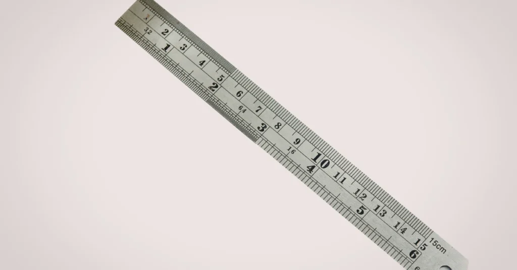 Metal ruler with inch and centimeter markings lying diagonally on a light background
