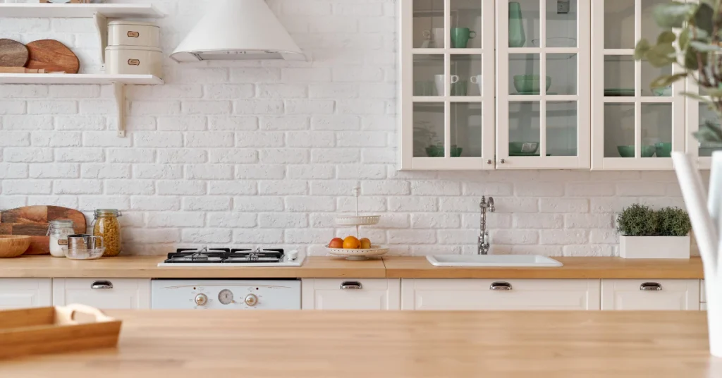 Bright white kitchen with wooden countertop and cabinets at standard counter height