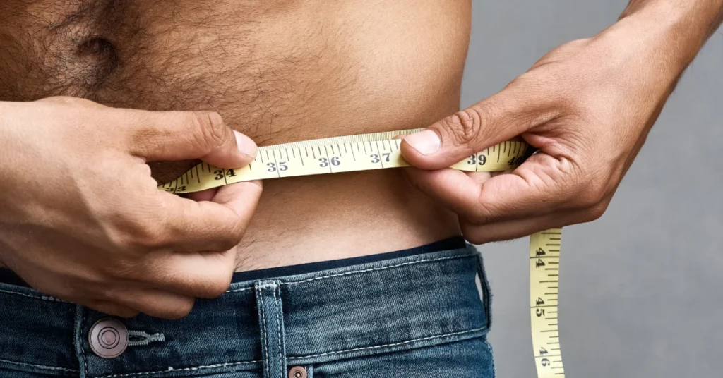 Estimating 4 inches in daily life, man measuring his waist with a tape measure