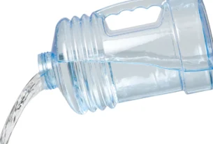 Large clear plastic water jug tilted while pouring out water