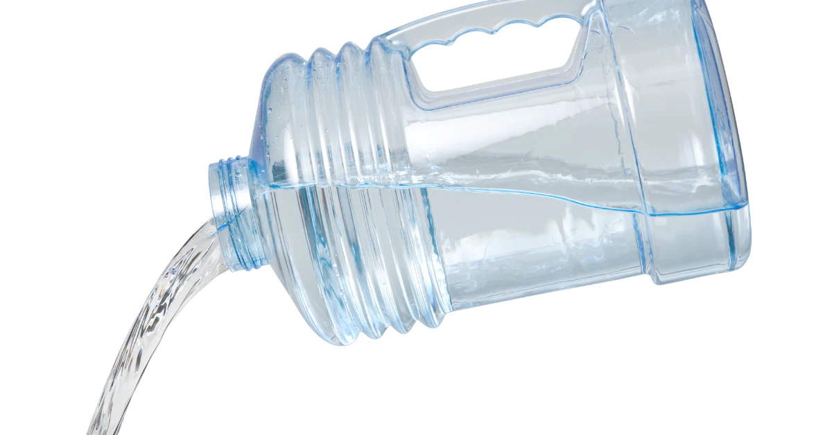 Large clear plastic water jug tilted while pouring out water