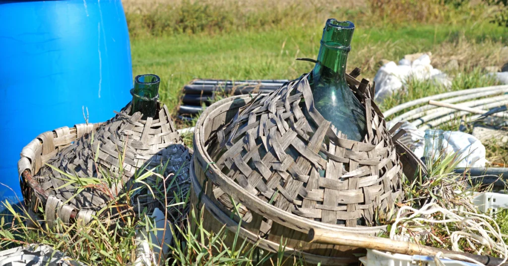 Blue plastic barrel next to a pile of wicker baskets on grass