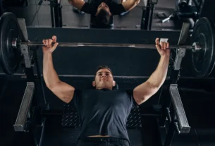Man performing a barbell bench press on a bench in a gym