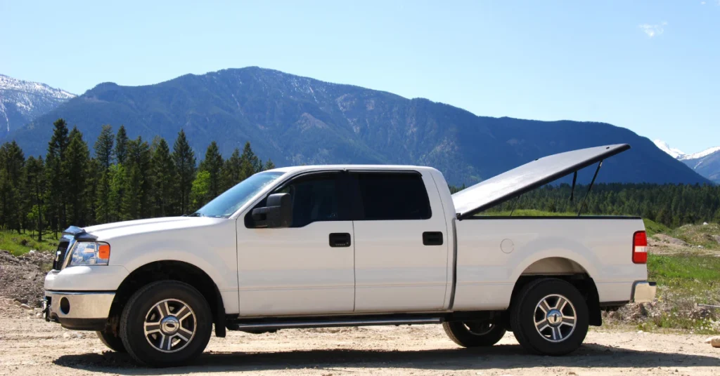 White half-ton pickup truck parked with mountains in the background