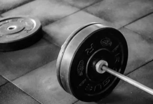 Barbell with weight plate on a gym floor, showing how much an EZ bar weighs