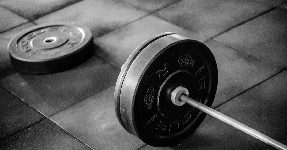 Barbell with weight plate on a gym floor, showing how much an EZ bar weighs